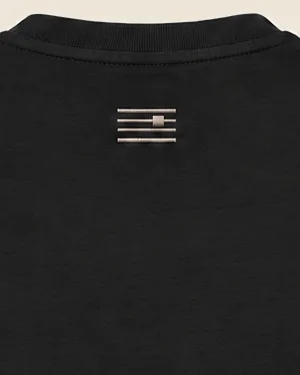 The back of the black tee below the collar, with the tetragram embroidered in stone thread.